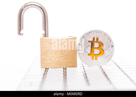 Digital currency, silver bitcoin with open padlock on keyboard Stock Photo