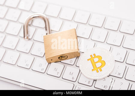 Digital currency, silver bitcoin with open padlock on keyboard Stock Photo