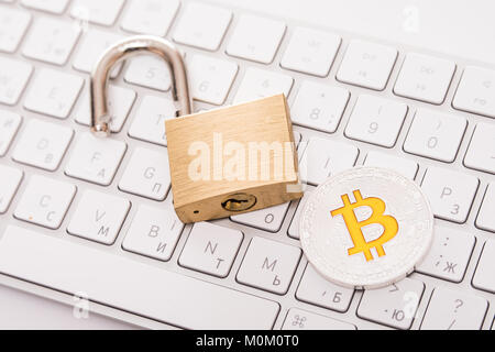 Digital currency, silver bitcoin with open padlock on keyboard Stock Photo