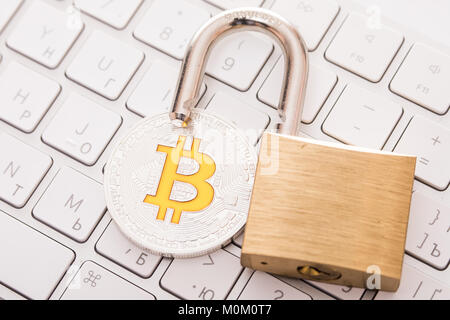 Digital currency, silver bitcoin with open padlock on keyboard Stock Photo