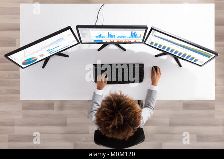 Businesswoman Analyzing Graph On Multiple Computers On Desk In Office Stock Photo
