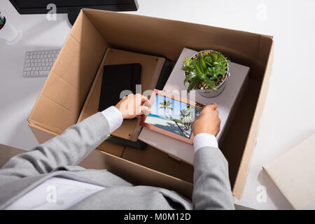 Close-up Of A Businesswoman Packing Picture Frame In Cardboard Box At Workplace Stock Photo