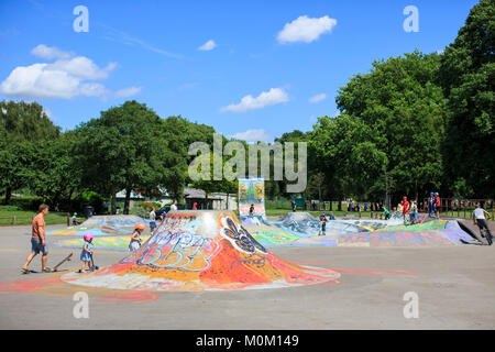 Children and adults use St George skatepark in Bristol on a sunny summer day. Stock Photo