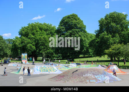 Children and adults use St George skatepark in Bristol on a sunny summer day. Stock Photo