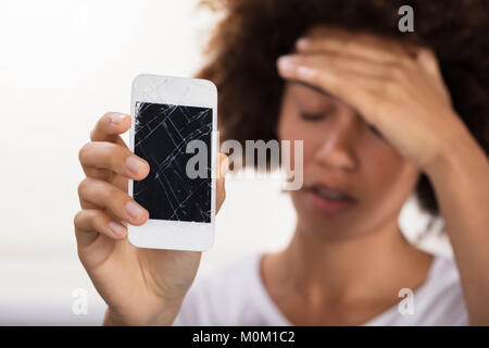 Close-up Of A Young Woman Holding Broken Mobile Phone Stock Photo