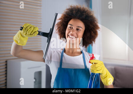 Smiling Young Woman Cleaning Glass Window With Squeegee Stock Photo