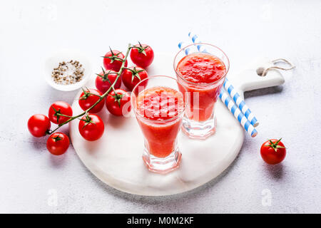 two glasses of freshly squeezed tomato juice on a marble serving board and cherry tomatoes. on a stone table Stock Photo