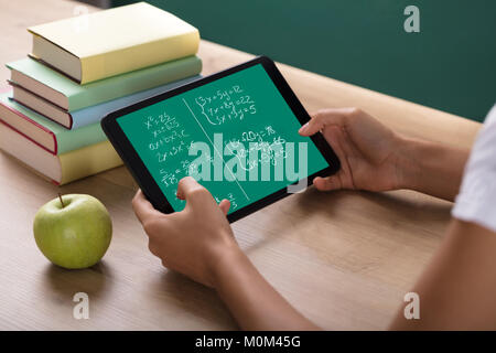 Close-up Of Human Hand Solving Math Problems On Digital Tablet In Classroom Stock Photo