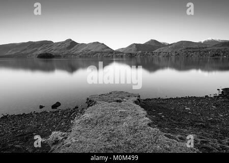 Mountains reflecting in a still cold Derwent Water on a crisp Lake District Winters morning. Stock Photo