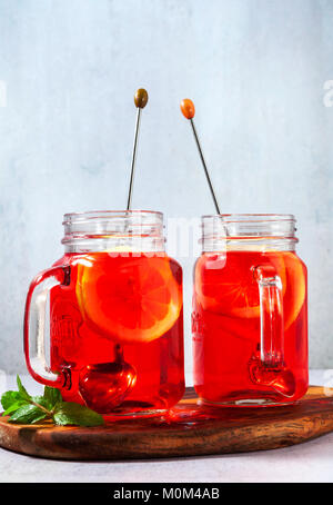 chilled karkade tea with lemon on a wooden stand on a stone table and background. antioxidants, spasmolytic, diuretic, antipyretic properties. Stock Photo