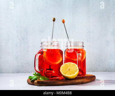 chilled karkade tea with lemon on a wooden stand on a stone table and background. antioxidants, spasmolytic, diuretic, antipyretic properties. Stock Photo