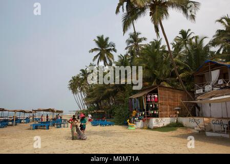 India,Goa,Morjim beach,woman seiling saris to a tourist in the beach lined with shops and coconut trees Stock Photo