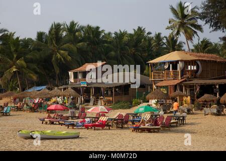 India,Goa,Patnem beach,tourists lying on deckchairs in the golden sand beach lined with coconut trees,near Palolem Stock Photo