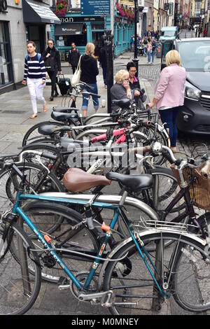 Pedestrians and bicycles locked in stand in street in center of Dublin in Ireland. Stock Photo