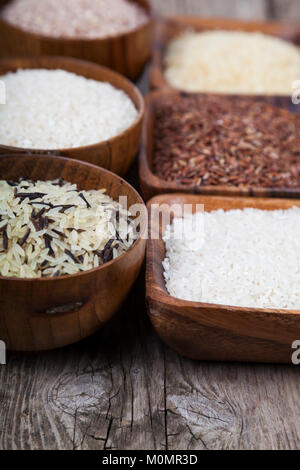 Six bowls with different varieties of rice on a wooden background. Ingredient for a healthy diet. Stock Photo