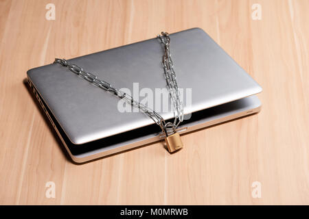 Heavy chain with a padlock around a laptop on table. Stock Photo