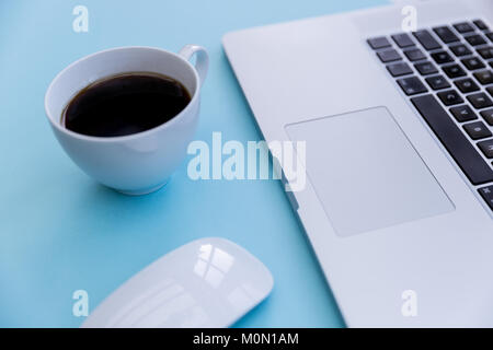 Laptop computer keyboard coffee and mouse on bright pastel blue background Stock Photo