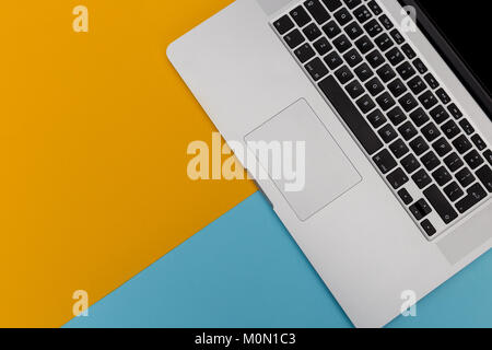 Laptop computer keyboard overhead on bright yellow and blue background with copy space Stock Photo
