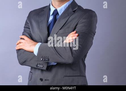 Young businessman standing with arms crossed on gray background Stock Photo