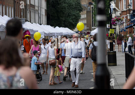 Crowd scene at the Marlyebone Summer Fayre Marlyebone Food Festival in London on a sunny day with yellow balloons and packed market stalls Stock Photo