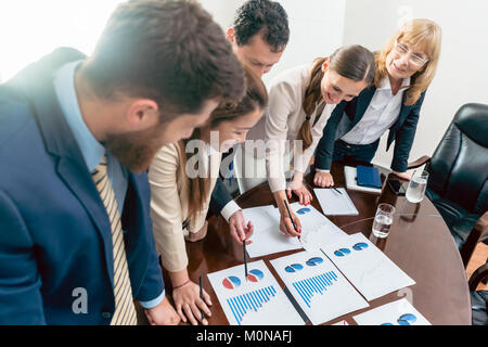 Multi-ethnic team of five dedicated specialists smiling while an Stock Photo