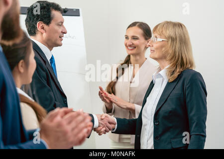 Two middle-aged business associates smiling while shaking hands  Stock Photo