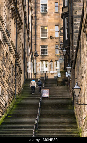 Couple climbing steep stairs Warriston's Close, Cockburn Street to Royal Mile, Edinburgh, Scotland, UK with tenement buildings and old fashioned lamps Stock Photo