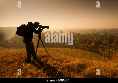 Silhouette of photographer taking landscape photos in morning. Stock Photo