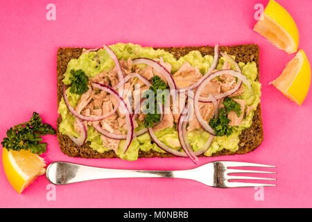 Tuna Fish and Avocado With Onions on Rye Bread Open Face Sandwich Against A Pink Background Stock Photo