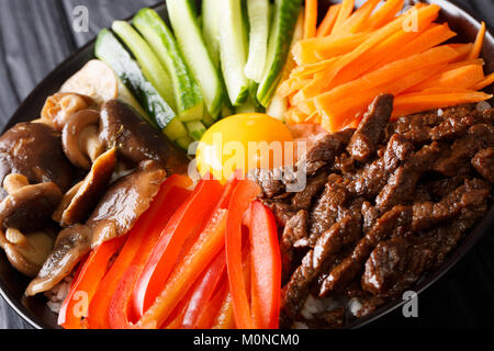 Bibimbap with beef, yolk, vegetables, mushrooms and rice macro on a plate. horizontal Stock Photo