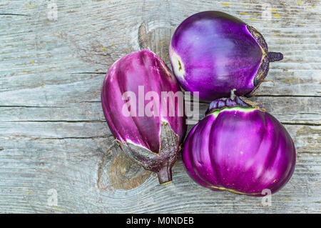 Purple eggplants closeup on a old gray wooden table Stock Photo