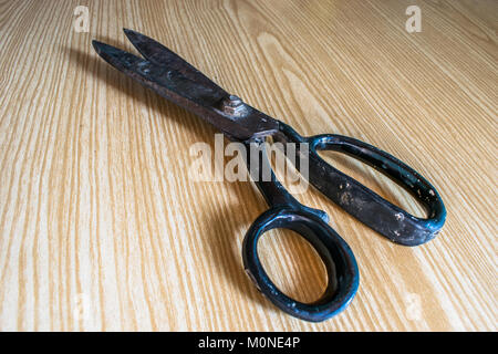 top view of an old and rusty scissor kept on a wooden table Stock Photo