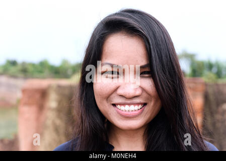 Portrait of a pretty asian millennial woman smiling at camera outdoors. Stock Photo