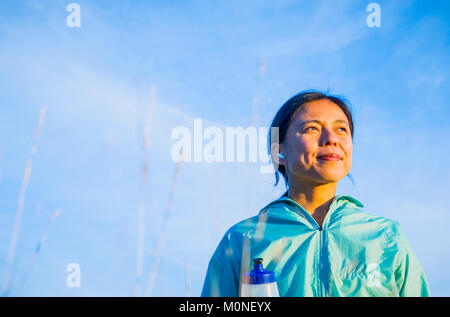 Portrait of a young Asian woman in outdoor activewear with ear buds in. Stock Photo
