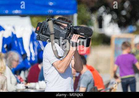 TV cameraman holding a professional Sony video camera for an outside broadcast in the UK. Stock Photo