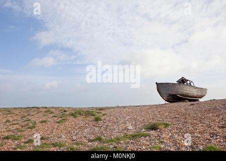 Old wrecked wooden shiplap fishing boat washed up on pebbles at Dungeness Kent coast.Old wrecked boat on beech