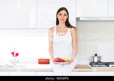Pregnant woman with fruits on the plate. Healthy eating concept Stock Photo