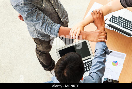 Business People Teamwork Meeting joining hands in triangle in the office concept, Using Ideas, Charts, Computers, Tablet, Smart devices on business pl Stock Photo