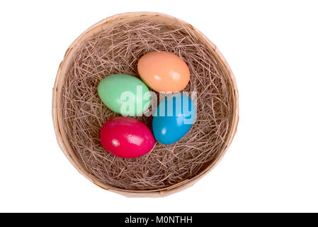 Four multi-colored eggs on straw in a wicker basket isolated on white Stock Photo