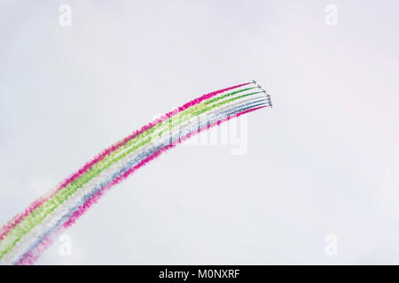 Airplanes on airshow with colorful bright trails of smoke against a blue sky, clouds. Aircraft, Airplane flying and aerobatic show Stock Photo