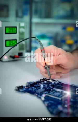 Electronic background, closeup on hands of tech fixing motherboard. Toned image, vignette, extra light effects. Shallow DOF, focus on the tester tool, Stock Photo