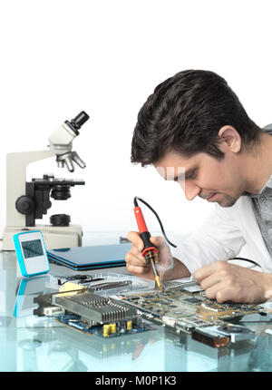 Young energetic male tech or engineer repairs electronic equipment, top of the picture isolated, space for your text, focus on the solrer tip and eyes Stock Photo