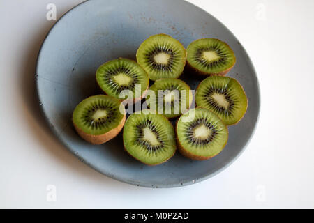Freshly cut kiwi fruit halves isolated on grey concrete plate Stock Photo