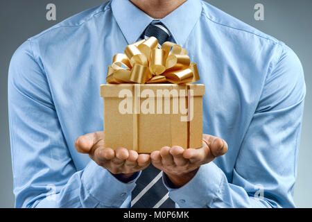 Man in blue shirt holding golden gift box. Close up. Business concept Stock Photo