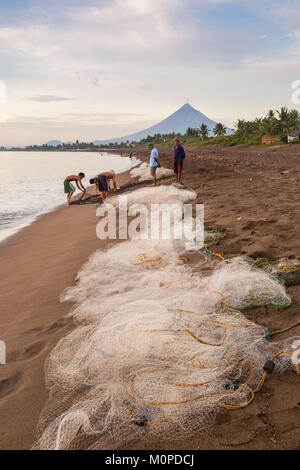 Philippines,Luzon,Albay Province,Tiwi,fishermen bringing a fishnet on the beach with Mayon volcano in back ground Stock Photo