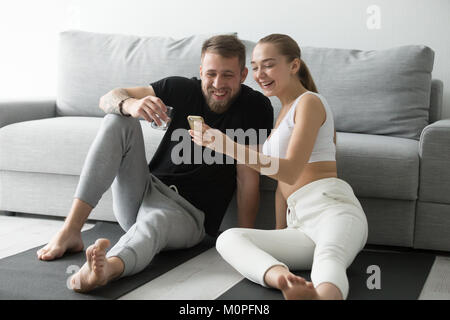 Fit happy couple using smartphone app for workout at home Stock Photo
