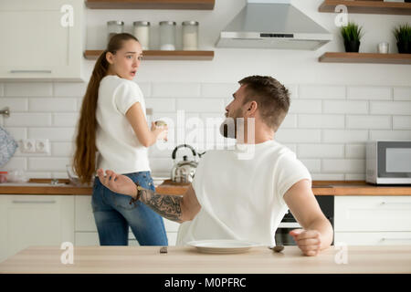 Angry husband and shocked wife arguing having conflict in kitche Stock Photo