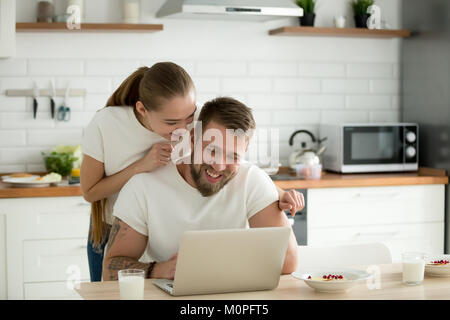 Happy young couple using laptop together in the kitchen Stock Photo