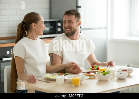 Happy young couple enjoying having breakfast at home kitchen tab Stock Photo