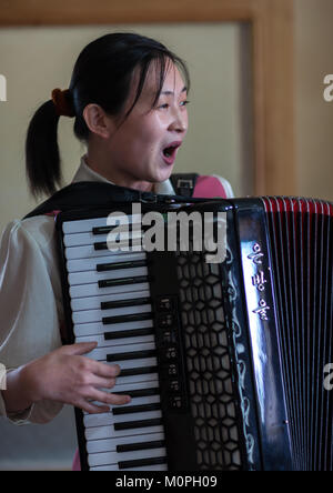 North Korean waitress in a restaurant singing and playing accordion, Pyongan Province, Pyongyang, North Korea Stock Photo